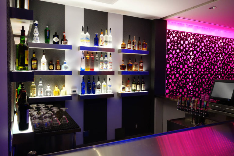 LED accent strip lights in pink and white, in a hotel bar accenting ceilings and walls, shelving and under counters. Boca Lighting and Controls.