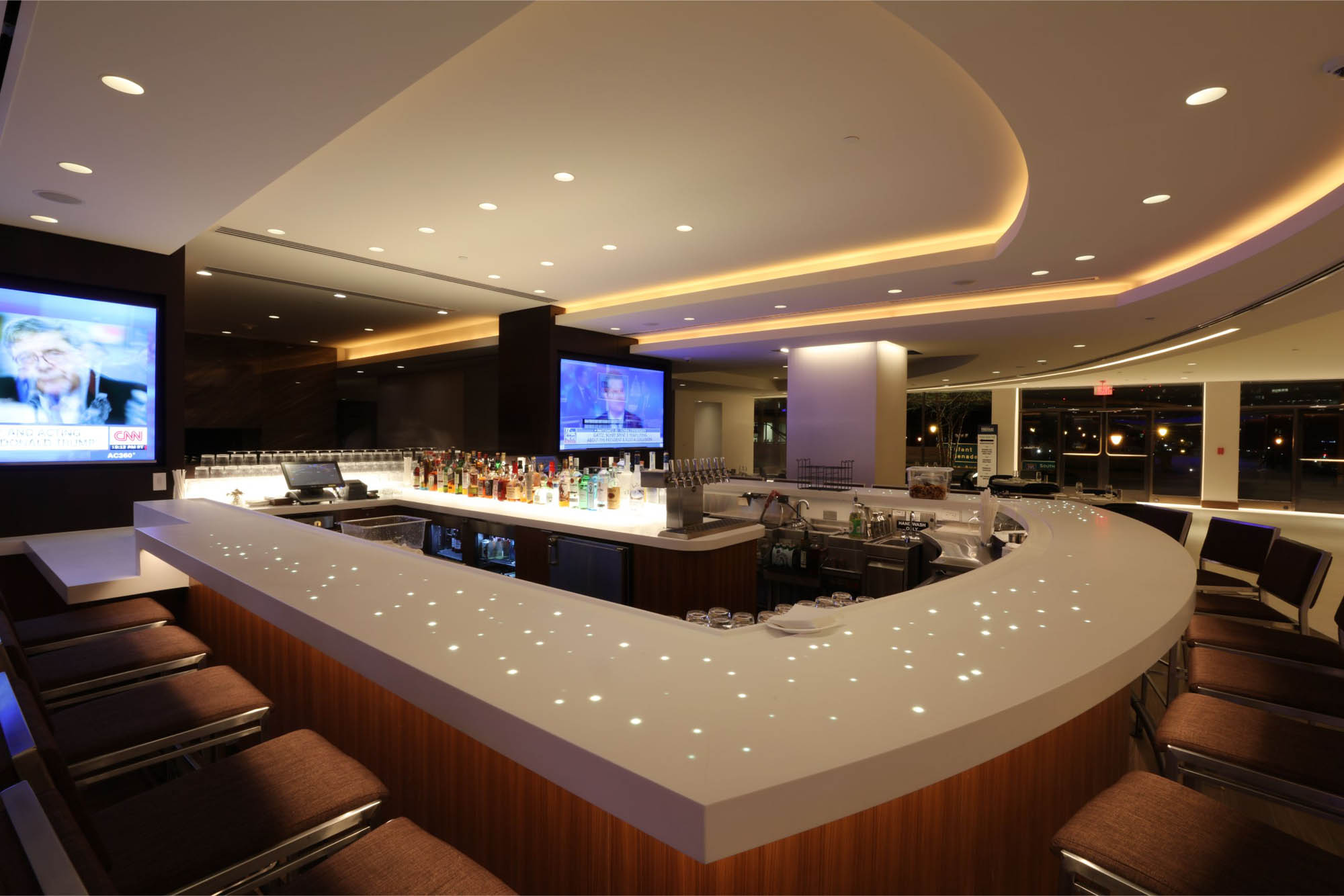 LED accent strip lights in a hotel bar and lobby accenting ceilings and walls, shelving and under counters. Boca Lighting and Controls.