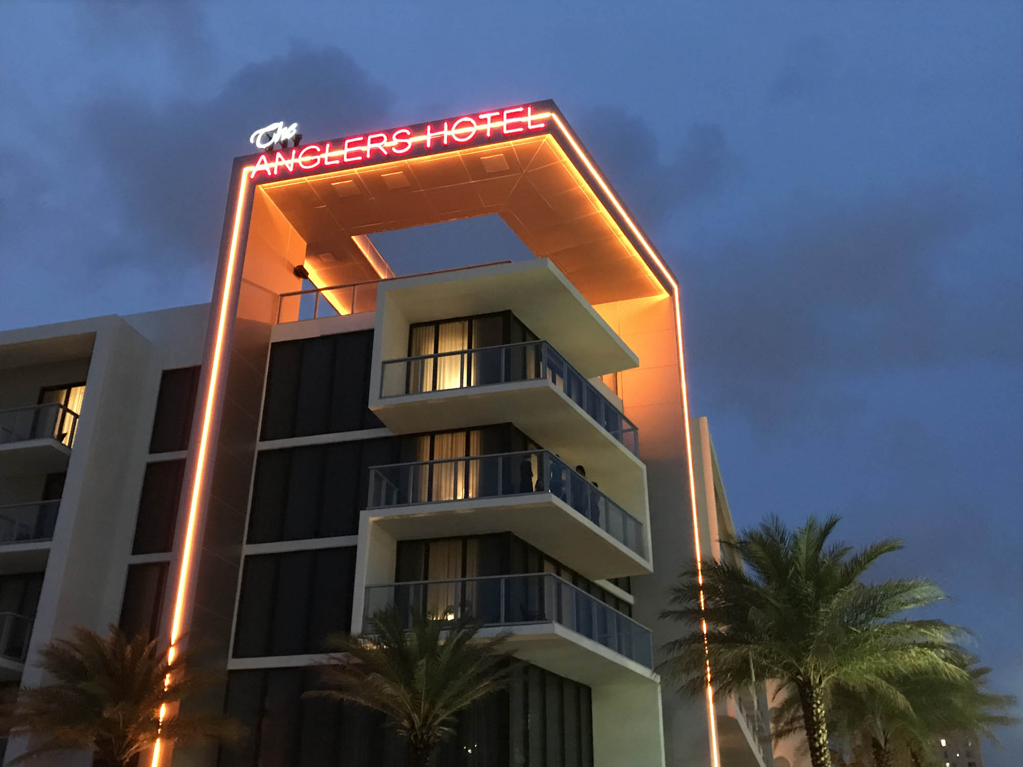 Orange linear LED lights illuminating architectural detail and the facade of a boutique hotel. Boca Lighting and Controls