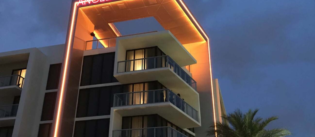 Orange linear LED lights illuminating architectural detail and the facade of a boutique hotel.
