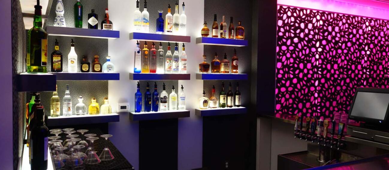 LED strip lights accent shelves in a hotel bar, emphasizing specific products.