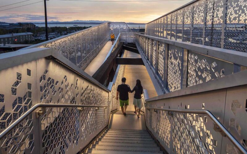 LED strip lights illuminate a pedestrian pathway and highlight the architecture on a bridge.