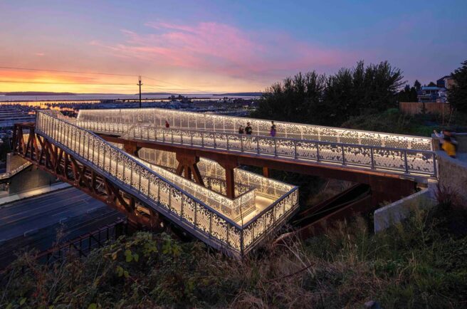 LED strip lights illuminate a pedestrian pathway and highlight the architecture on a bridge.
