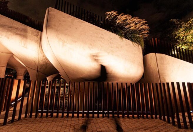 LED wall washing and façade lighting fixtures illuminate modern elevated walkways in an outdoor garden.