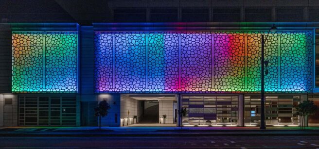LED screen and cove lighting illuminate the exterior of the Luma Hotel in a multicolor display.