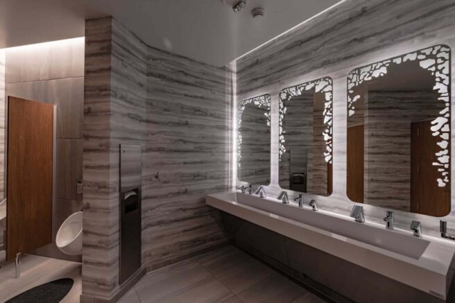 LED strip lighting and cove lighting illuminate a men's restroom in the Luma Hotel.